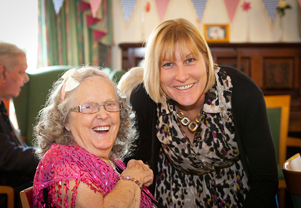Carer and customer holding hands laughing.